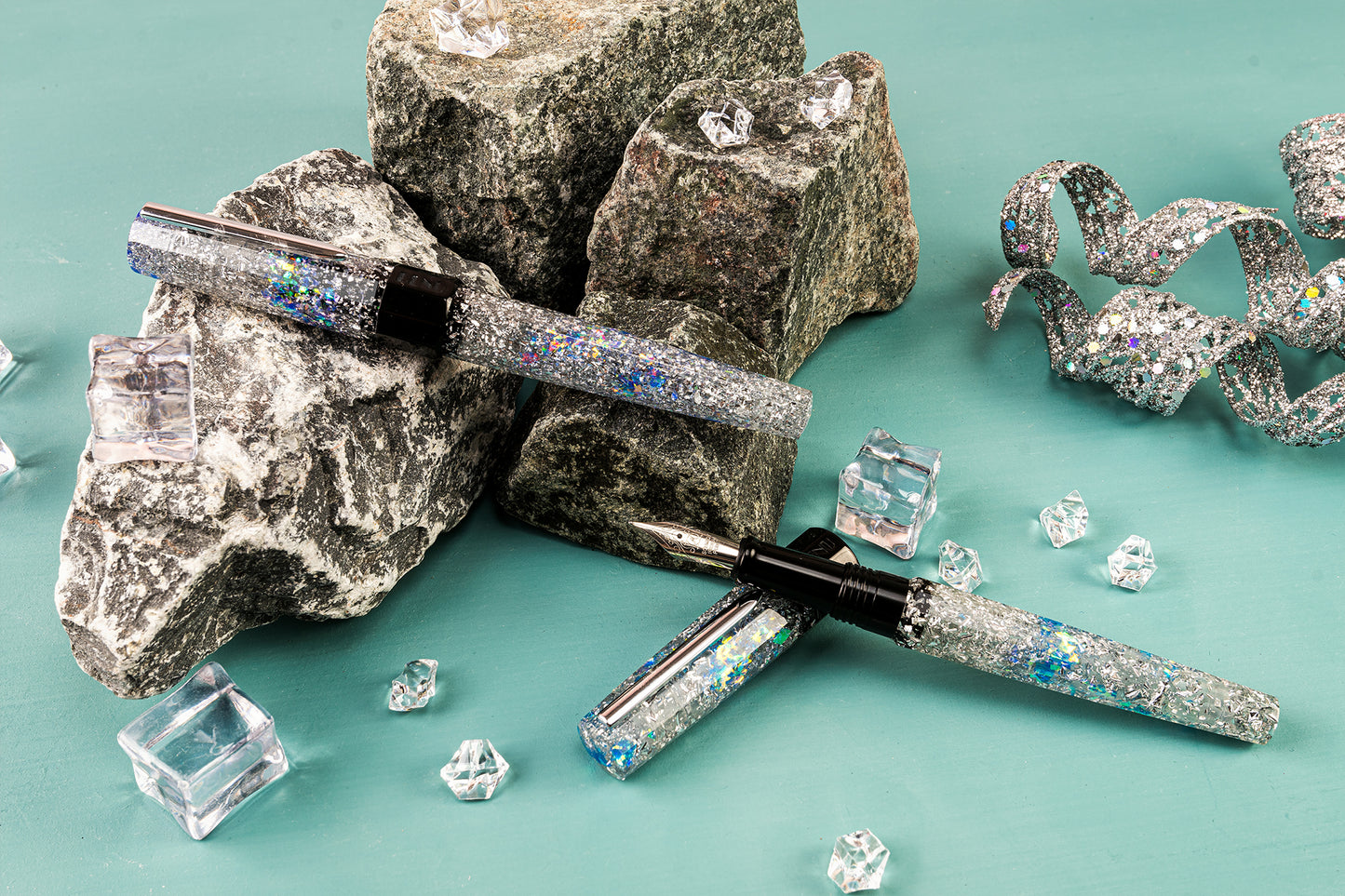 Fountain pen with glittery accents on a teal background with rocks and crystals.