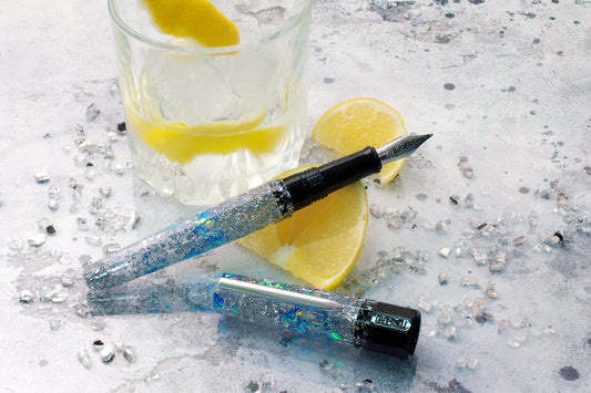 A sparkling fountain pen next to a drink with lemons.