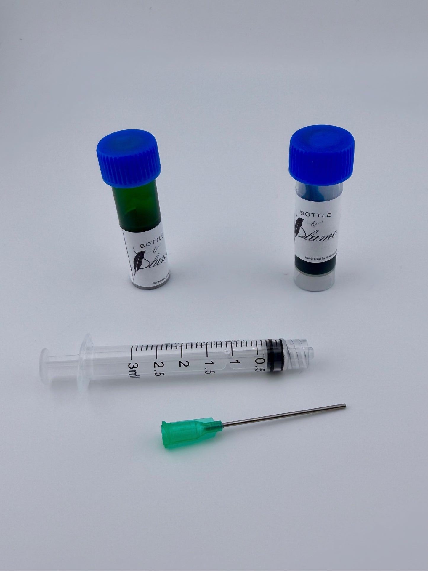 Two fountain pen ink vials with blue caps and a blunt-tip syringe with a needle on a white background