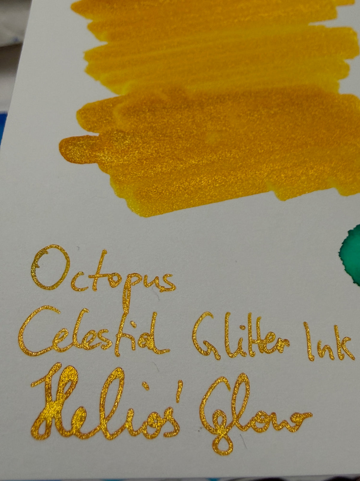 Octopus Celestial Glitter Helios' Glow: ink swatch and handwritten label showing reflective shimmer.
