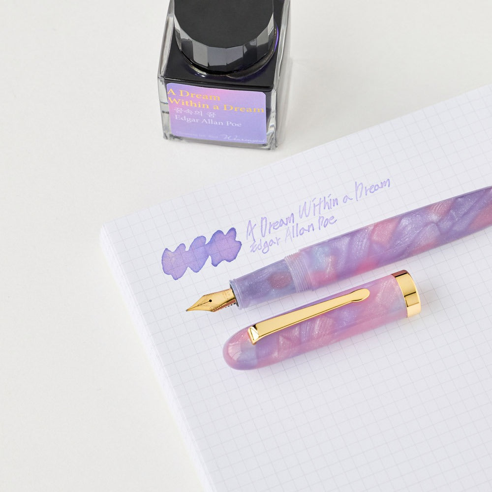 Wearingeul A Dream Within a Dream fountain pen on a notebook beside matching ink, sold separately